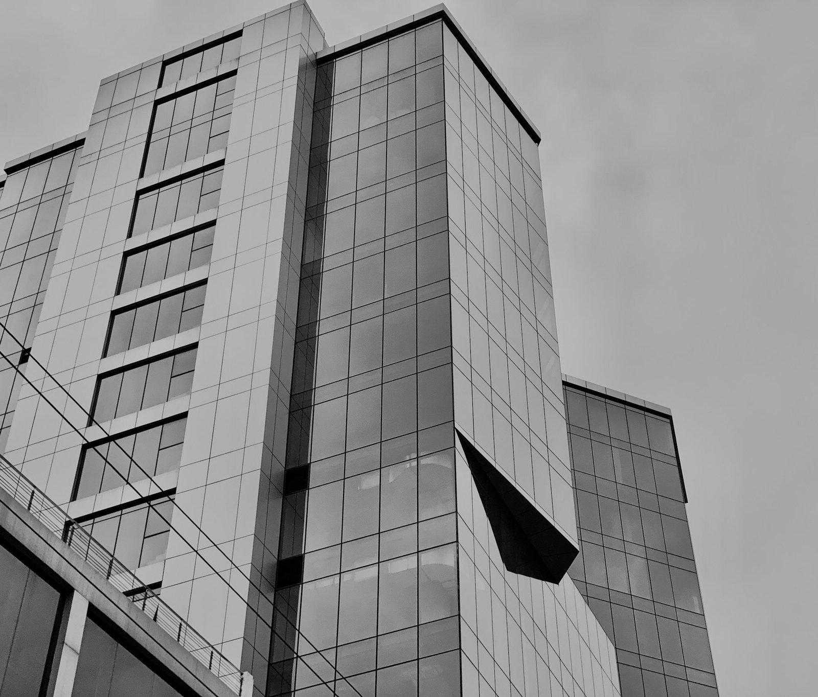 A glass office tower rising into an overcast sky